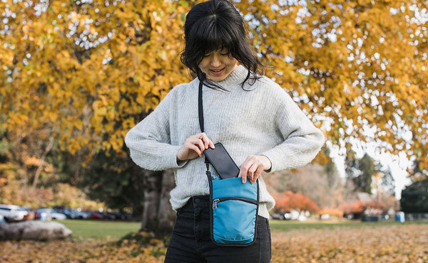 A person accessing their phone from the phone pocket of the P.I.K.A. Pouch.